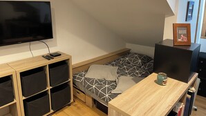 A small, modern bedroom with a bed, a TV, and a desk. - Studio MODERNE (Barcelonnette)