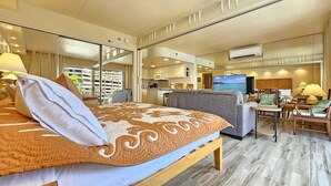 Une chambre d’hôtel comprenant un lit, un canapé, une télévision, un bureau et un coin cuisine.