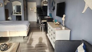 Une petite chambre comprenant un lit, un bureau, une chaise, une commode et un téléviseur.