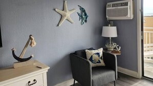 Une pièce avec un mur gris, une décoration en forme d’étoile de mer, une lampe, une chaise et une commode en bois.