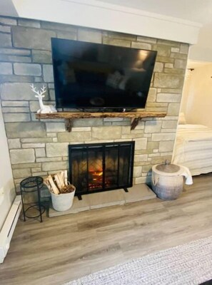 Cozy living room with a fireplace, flat-screen TV, and a small table.
