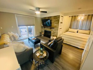 Relax in a cozy space with a flat-screen TV, comfortable sofa, and a bed, plus a sliding door leading to an outdoor area.