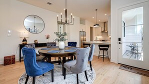 A modern dining room with a round table, blue and grey upholstered chairs, a chandelier, and a large mirror on the wall. - Charming Luxury Home near Heights & close to Downtown-The Houston oasis . (Houston)