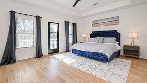 A bedroom with a bed, two bedside tables, a ceiling fan, and a large window with curtains. - Charming Luxury Home near Heights & close to Downtown-The Houston oasis . (Houston)