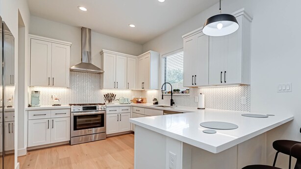 A modern kitchen with white cabinetry, a central island, stainless steel appliances, and a herringbone tile backsplash. - Charming Luxury Home near Heights & close to Downtown-The Houston oasis . (Houston)