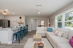A modern living space with a kitchen, dining area, and a large sofa.