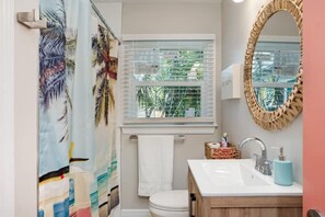 Une salle de bain avec une fenêtre, des toilettes, un lavabo et un miroir.