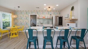 A modern kitchen with a central island, yellow chairs, and teal chairs. - Colorful home with game area (Bradenton)
