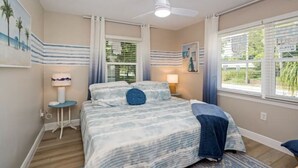 A bedroom with a bed, a ceiling fan, a window with blinds, and a painting on the wall. - Colorful home with game area (Bradenton)