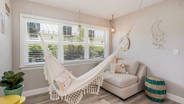 A room with a hammock, a sofa, a round table, and a potted plant. - Colorful home with game area (Bradenton)