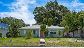 Stroll through the serene front yard, surrounded by mature trees and a small pathway leading to the entrance.