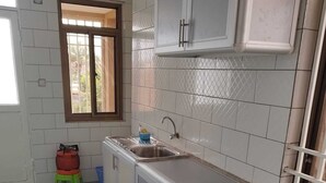 Eine Küche mit weißen Schränken, einem Spülbecken, einem Herd und einem Fenster mit Blick.