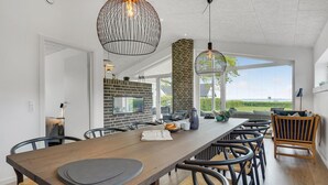 Une cuisine moderne avec une longue table en bois, des chaises noires et des luminaires suspendus.