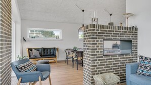 Un salon moderne avec une cheminée en briques, un canapé, une table à manger et une grande fenêtre.