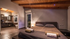 Un dormitorio moderno con una cama grande, techo de madera y un baño con lavamanos y espejo.