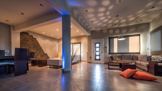 Un amplio salón con una escalera de piedra, un ventanal grande y un sofá moderno.