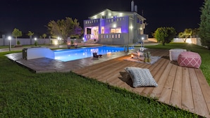 Una casa moderna con piscina, terraza de madera y zona de estar al aire libre de noche.