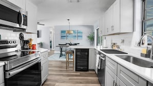 Une cuisine moderne dotée d’appareils électroménagers en acier inoxydable, un coin repas avec vue et un petit îlot central.