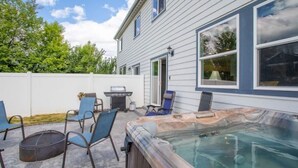 Ein Garten mit Whirlpool, Terrassenstühlen, Grill und überdachter Sitzgelegenheit.