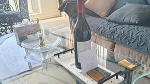 A glass-top table with a bottle of wine, a candle, and a sign that reads "Happy Stay". - Spacious 1 Bed Apartment, parking, gym, pool (Gungahlin)