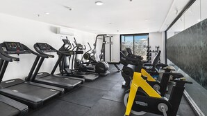 A modern gym with treadmills, elliptical machines, and a stationary bike. - Spacious 1 Bed Apartment, parking, gym, pool (Gungahlin)