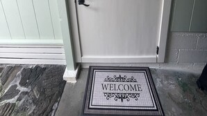 A white door with a black handle, a welcome mat, and a mailbox. - One bedroom studio private (Kealakekua)