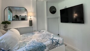 A bedroom with a bed, a ceiling fan, a wall clock, and a TV. - One bedroom studio private (Kealakekua)