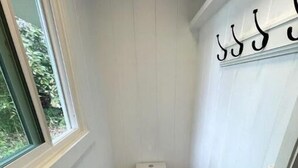 A small, narrow bathroom with a toilet, a window, and a door. - One bedroom studio private (Kealakekua)