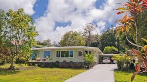 A single-story house with a front porch, a driveway, and a car parked in the driveway. - One bedroom studio private (Kealakekua)