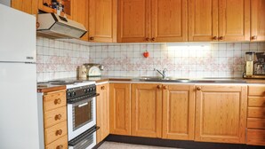 A kitchen with wooden cabinets, a stove, a sink, and a coffee maker.