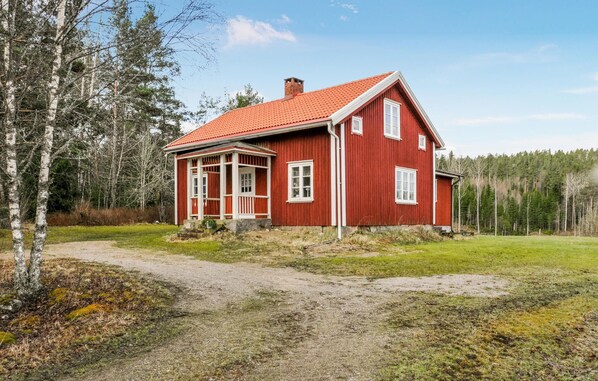 Traditional home with a front porch and steps leading to the entrance, set amidst a rural forest backdrop.