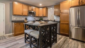 Una cocina moderna con armarios de madera, un refrigerador de acero inoxidable y una isla central con taburetes.