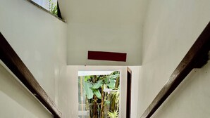 A staircase leading to a covered outdoor area with a view of a garden. - Suítes D'Ajuda Inn (Porto Seguro)