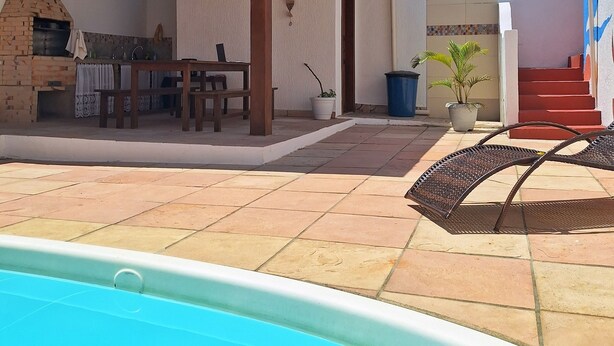 A poolside area with a barbecue, outdoor seating, and a staircase leading to a building. - Suítes D'Ajuda Inn (Porto Seguro)