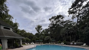 Une piscine rectangulaire avec une terrasse carrelée, entourée de chaises longues et de parasols.