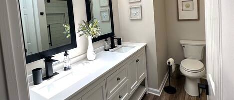 A bathroom with a skylight, a large mirror, a white sink, and a toilet.