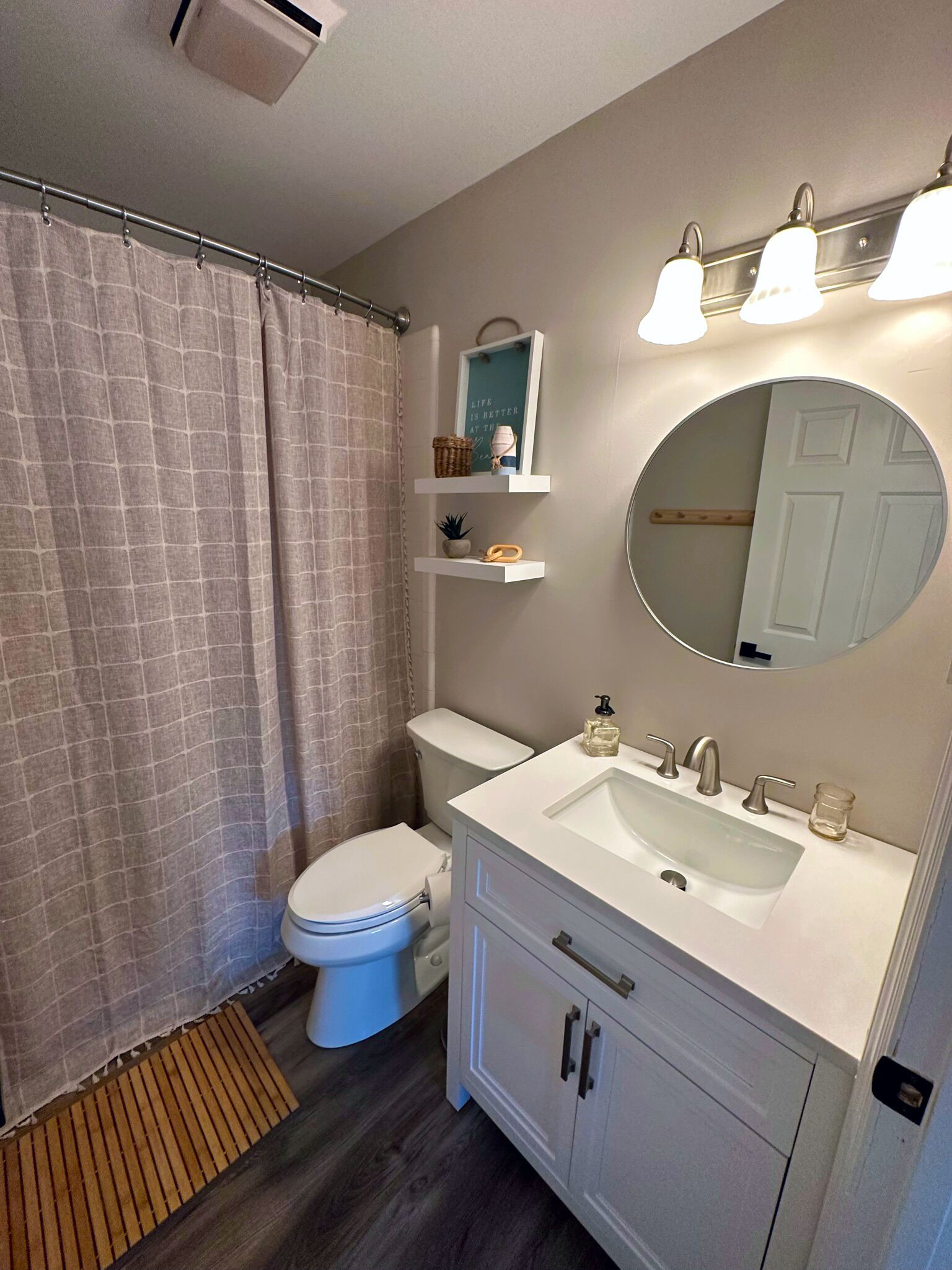 Un baño con inodoro, lavabo, espejo y cortina de ducha.