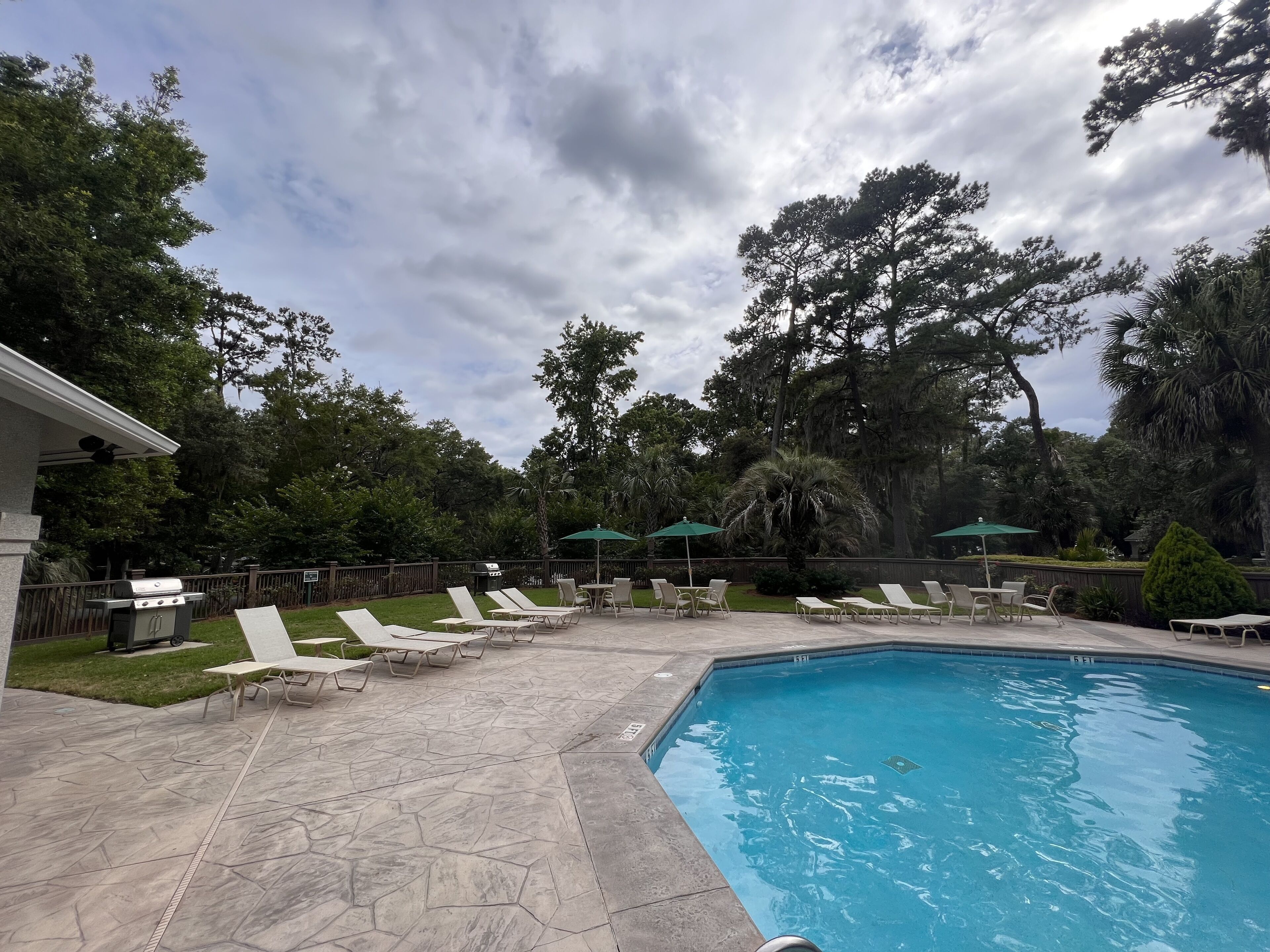 Um quintal com piscina, espreguiçadeiras e churrasqueira.
