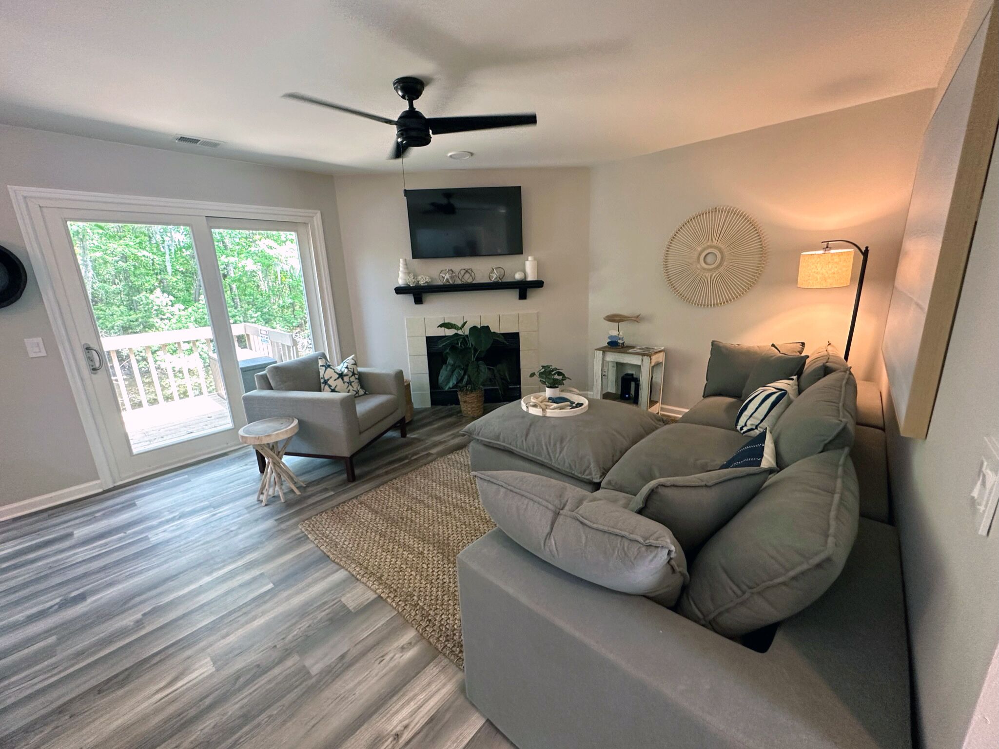 A spacious living room with a large sectional sofa, a fireplace, and a ceiling fan.