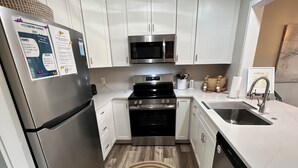 Une cuisine moderne dotée d’appareils électroménagers en acier inoxydable, de meubles blancs et d’un plancher en bois.