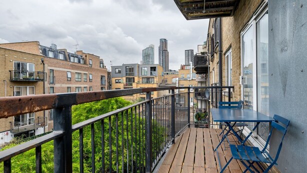 A balcony with a wooden floor, blue chairs, and a table. - GuestReady - Trendy stay near Brick Lane Market (London)