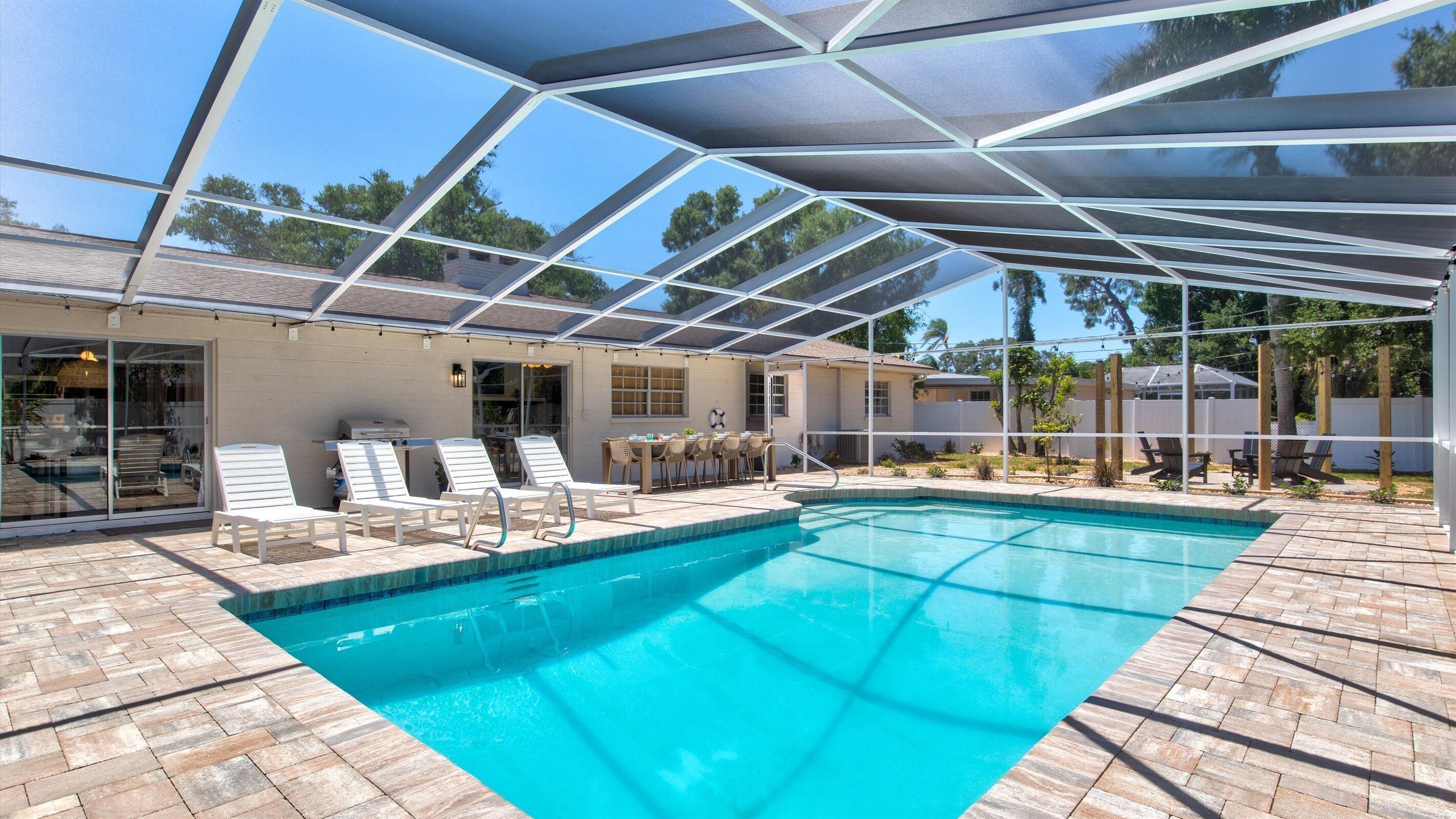 Une piscine avec un patio couvert, des chaises longues et une table.