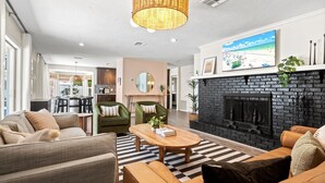 Un salon moderne avec une cheminée, un coin repas et une cuisine en arrière-plan.