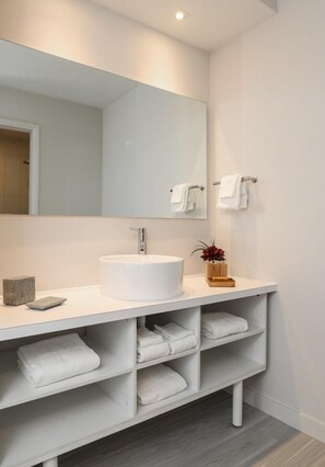 Features a sleek vanity with a large round sink and matching mirror.