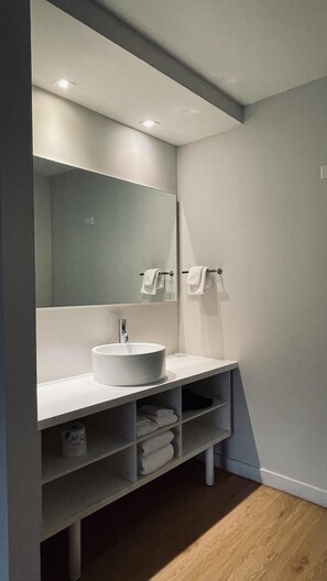 Bathroom features a large mirror above a sink, two towel racks, and shelves for additional storage.