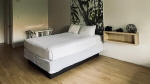 Ein Schlafzimmer mit einem Bett, einem Schreibtisch und einem an der Wand befestigten Regal.