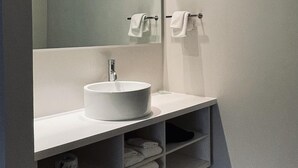 A modern bathroom with a large mirror, a white sink, and a towel rack. - Deluxe Apartment Two Queen (Kissimmee)