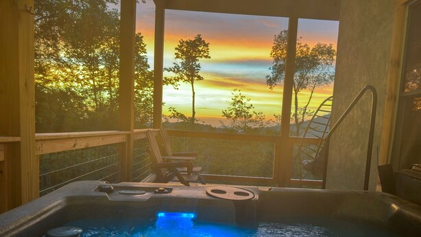 A hot tub with a view of a sunset, a wooden deck, and a chair. - Sunset Mtn View*Pool*Hot Tub*Massage Chair*Theater Rm*Pickleball*Game Rm*Hiking (Mars Hill)