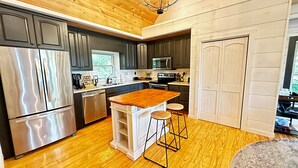 A modern kitchen with stainless steel appliances, a wooden island with stools, and a view of the outdoors. - Sunset Mtn View*Pool*Hot Tub*Massage Chair*Theater Rm*Pickleball*Game Rm*Hiking (Mars Hill)