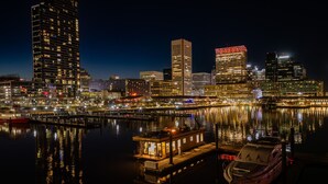 Een verlicht stadsgezicht bij nacht, met gebouwen die hun licht in het rustige water weerspiegelen.